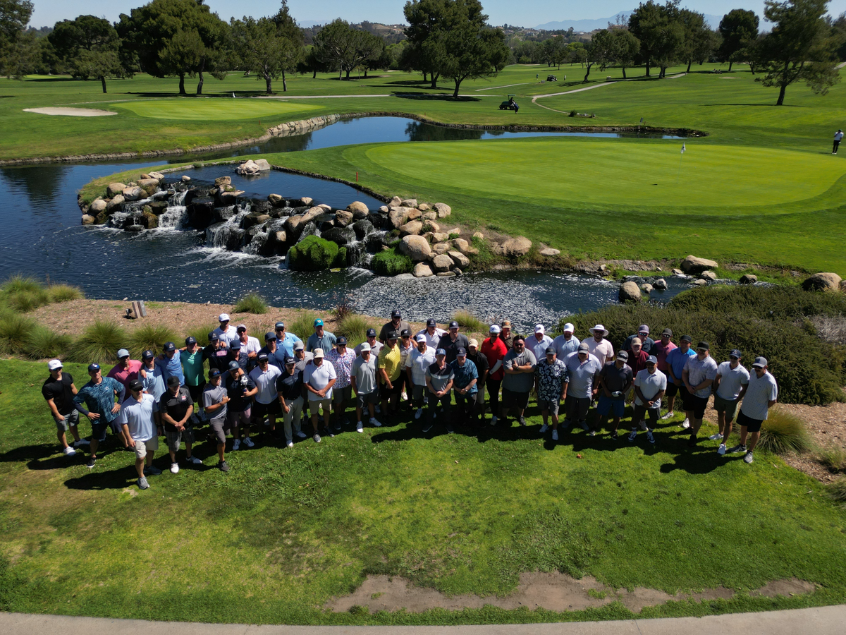The full field at Fairways for the Fallen, Temecula Creek Inn, gathered beside the water on the course.